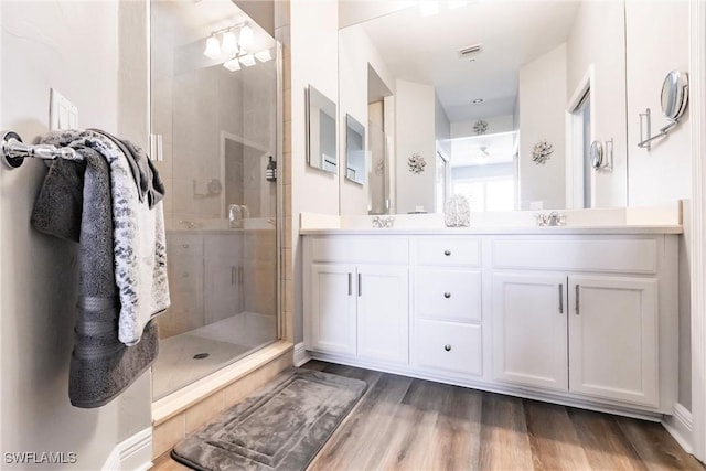 full bath featuring a stall shower, double vanity, and wood finished floors