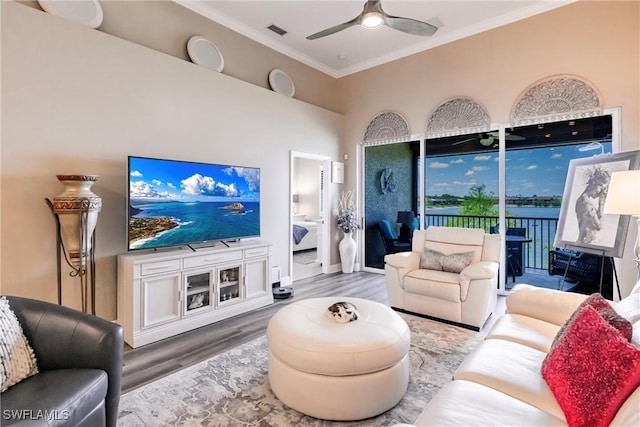 living area featuring ornamental molding, wood finished floors, a ceiling fan, a high ceiling, and baseboards