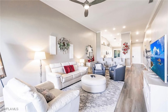 living area with ceiling fan, light wood-style floors, ornamental molding, baseboards, and recessed lighting