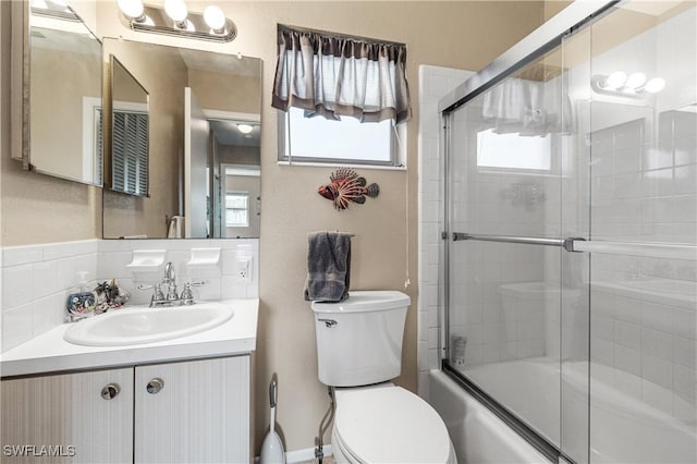 bathroom with toilet, vanity, and bath / shower combo with glass door