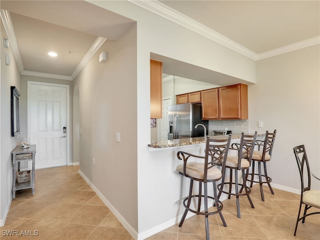 17961 Bonita National Blvd Unit 514, Bonita Springs, FL 34135 - kitchen with brown cabinetry, stainless steel fridge, ornamental molding, light tile patterned floors, and tasteful backsplash
