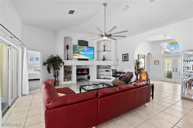 2005 SE 21st St, Cape Coral, FL 33990 - living room with arched walkways, light tile patterned floors, built in features, ceiling fan, and a glass covered fireplace