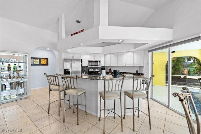 2005 SE 21st St, Cape Coral, FL 33990 - kitchen with stainless steel appliances, light tile patterned floors, white cabinets, a breakfast bar area, and arched walkways