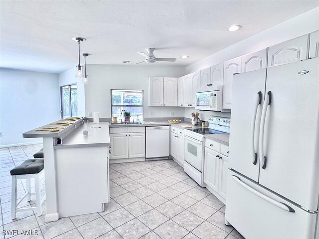 844 106th Ave N, Naples, FL 34108 - kitchen with white appliances, a peninsula, white cabinets, a breakfast bar area, and a sink
