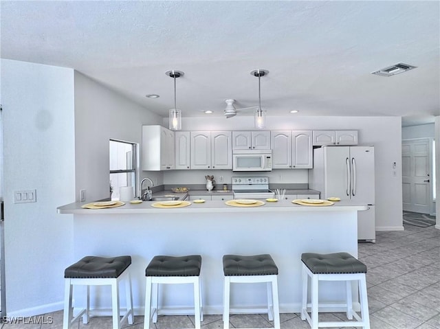844 106th Ave N, Naples, FL 34108 - kitchen with white appliances, a peninsula, a kitchen bar, decorative light fixtures, and baseboards