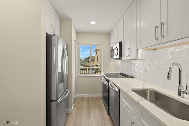 7400 Estero Blvd Unit 125, Fort Myers Beach, FL 33931 - kitchen with stainless steel appliances, a sink, tasteful backsplash, white cabinetry, and baseboards