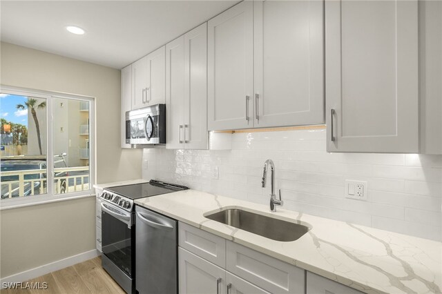 7400 Estero Blvd Unit 125, Fort Myers Beach, FL 33931 - kitchen featuring appliances with stainless steel finishes, a sink, light wood-style flooring, decorative backsplash, and recessed lighting