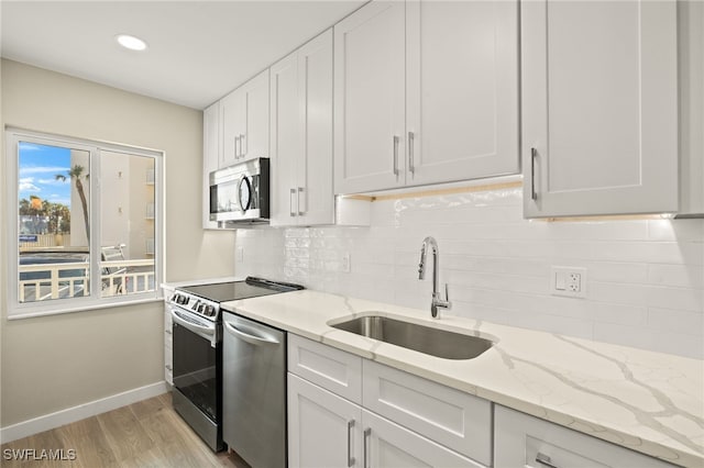 7400 Estero Blvd Unit 125, Fort Myers Beach, FL 33931 - kitchen with stainless steel appliances, a sink, baseboards, light wood-type flooring, and white cabinetry