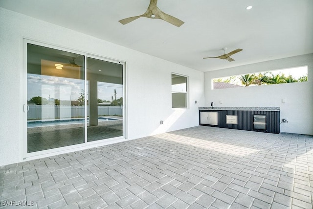 view of patio / terrace with a ceiling fan, fence, exterior kitchen, and wine cooler