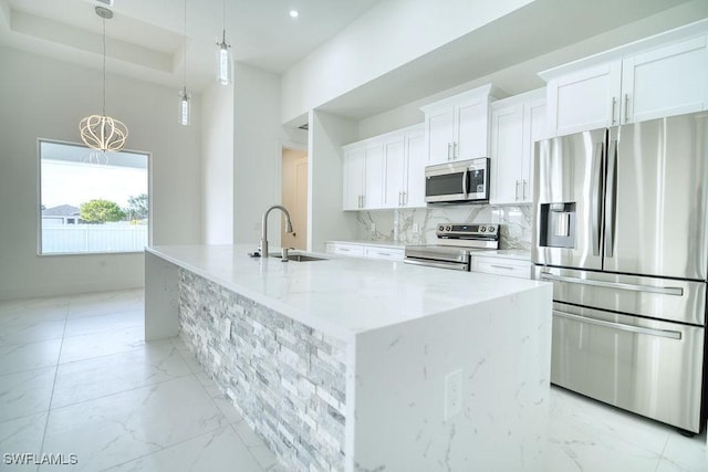 kitchen with stainless steel appliances, a sink, light marble finish flooring, white cabinets, and a large island with sink