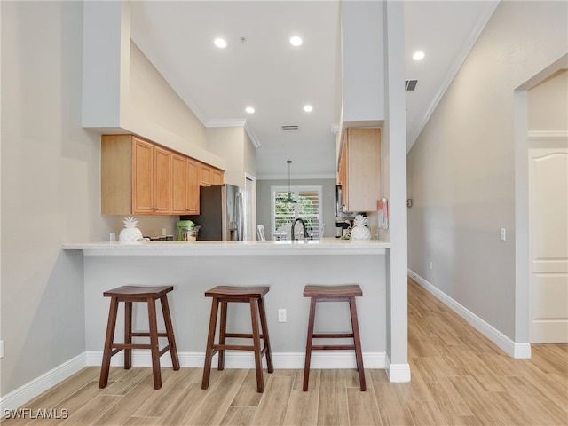 19920 Barletta Ln Unit 1423, Estero, FL 33928 - kitchen featuring stainless steel fridge with ice dispenser, crown molding, light wood-type flooring, a kitchen breakfast bar, and light countertops