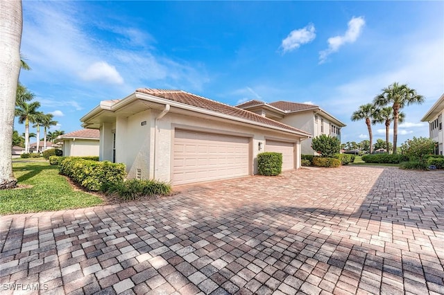 view of front of home featuring stucco siding, decorative driveway, a garage, and a tile roof