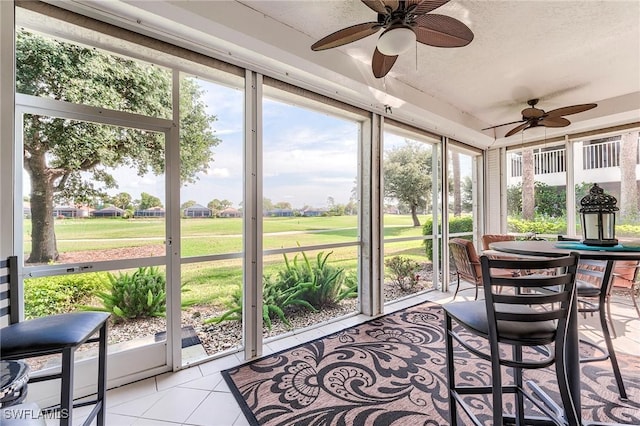 sunroom / solarium with a ceiling fan and golf course view