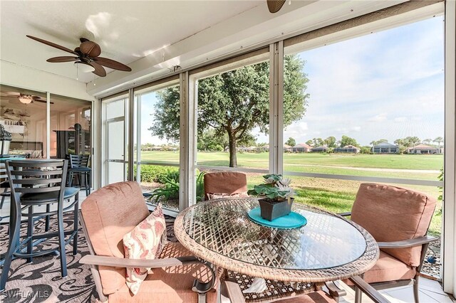 sunroom / solarium featuring a ceiling fan and outdoor dining area