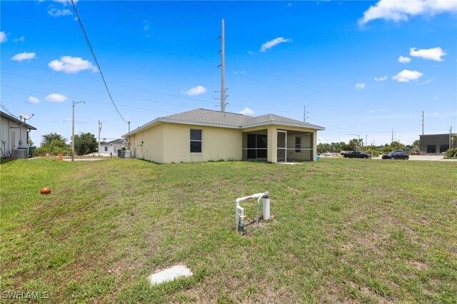 706 Kismet Pkwy E, Cape Coral, FL 33909 - rear view of house with a sunroom, a yard, and central AC