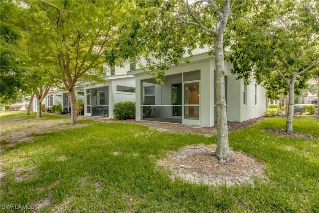 19530 Bowring Park Rd Unit 106, Fort Myers, FL 33967 - rear view of property with stucco siding, a lawn, and a sunroom