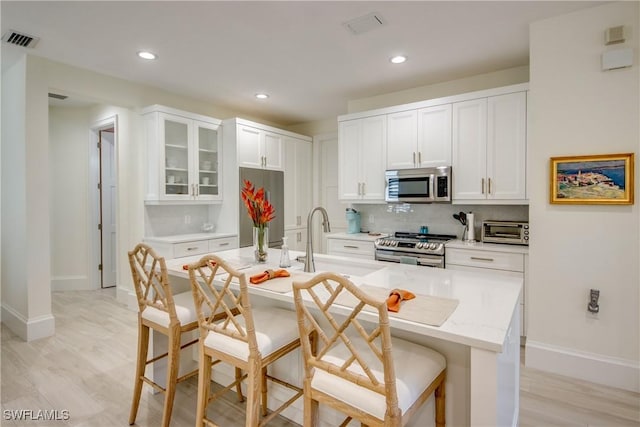 9373 Aviano Dr, Fort Myers, FL 33913 - kitchen featuring appliances with stainless steel finishes, tasteful backsplash, glass insert cabinets, white cabinetry, and recessed lighting