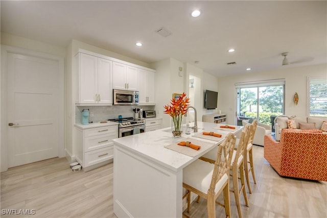 9373 Aviano Dr, Fort Myers, FL 33913 - kitchen featuring appliances with stainless steel finishes, open floor plan, white cabinetry, recessed lighting, and tasteful backsplash
