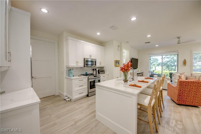 9373 Aviano Dr, Fort Myers, FL 33913 - kitchen featuring stainless steel appliances, open floor plan, white cabinets, recessed lighting, and light wood-type flooring