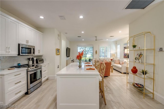 9373 Aviano Dr, Fort Myers, FL 33913 - kitchen featuring appliances with stainless steel finishes, open floor plan, white cabinets, a center island, and backsplash
