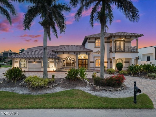 mediterranean / spanish-style house with a balcony, stucco siding, french doors, and a tile roof
