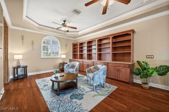 sitting room with ceiling fan, a raised ceiling, dark wood-type flooring, baseboards, and ornamental molding