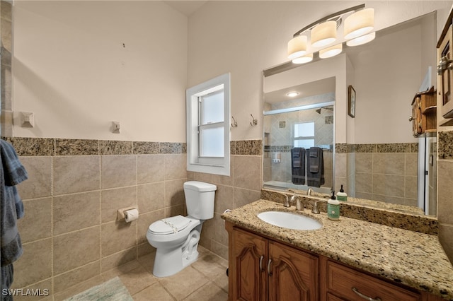 bathroom featuring tile walls, tile patterned floors, a stall shower, toilet, and wainscoting