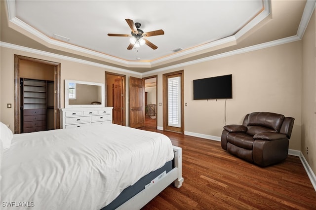 bedroom featuring a raised ceiling, wood finished floors, crown molding, baseboards, and a ceiling fan