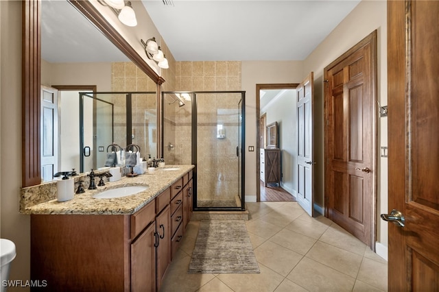 bathroom with a stall shower, double vanity, tile patterned floors, and baseboards