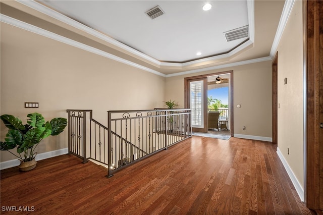 empty room with wood finished floors, baseboards, a tray ceiling, ornamental molding, and recessed lighting