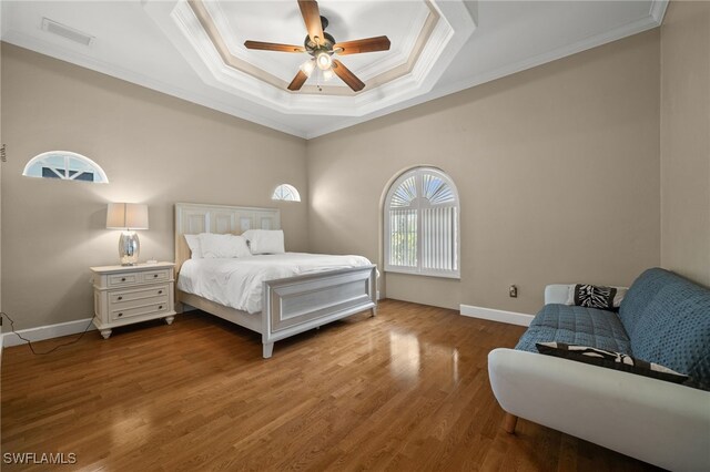 bedroom featuring ornamental molding, wood finished floors, a raised ceiling, ceiling fan, and baseboards