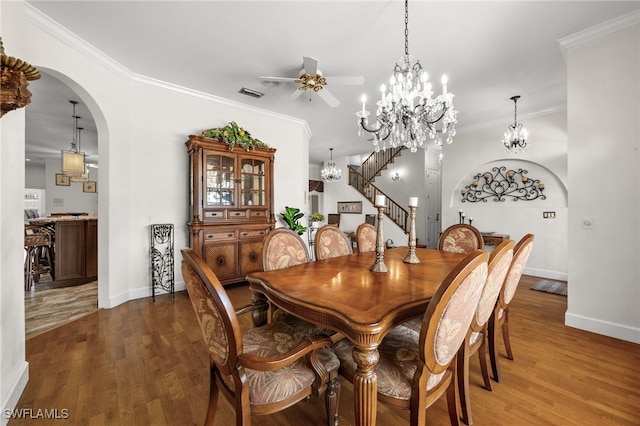 dining room with arched walkways, wood finished floors, baseboards, a ceiling fan, and ornamental molding