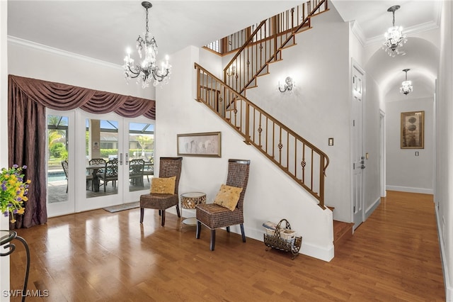 sitting room featuring a chandelier, ornamental molding, wood finished floors, stairway, and baseboards