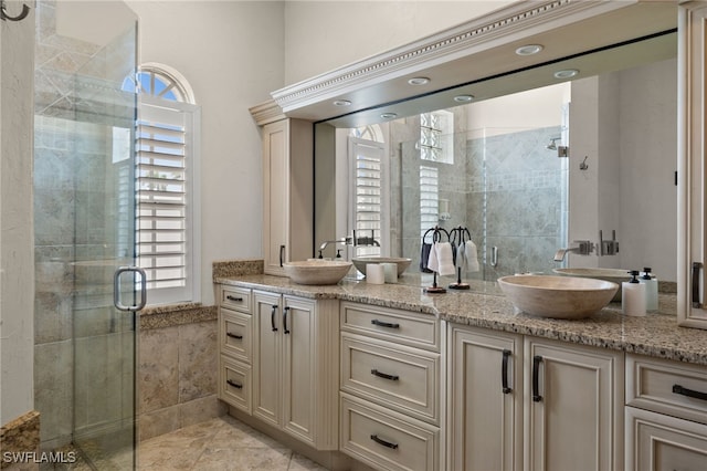 full bath with healthy amount of natural light, a shower stall, double vanity, tile walls, and a wainscoted wall