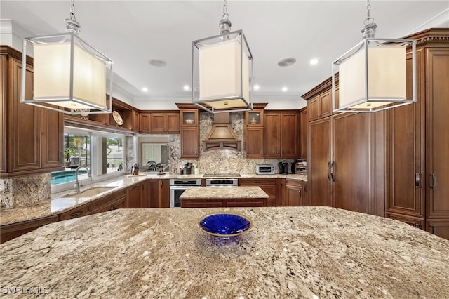kitchen with a sink, oven, brown cabinetry, light stone countertops, and glass insert cabinets