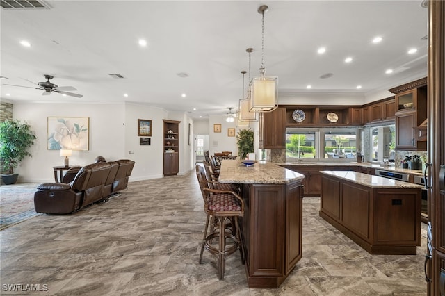 kitchen featuring ceiling fan, crown molding, open floor plan, a kitchen island, and recessed lighting