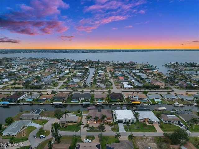 aerial view at dusk of a water view and a residential view
