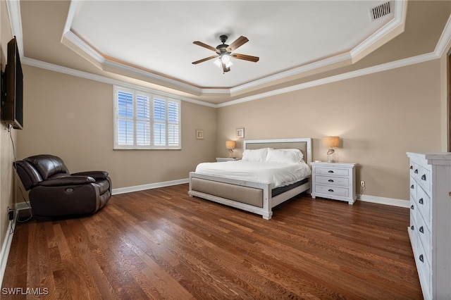 bedroom featuring a tray ceiling, dark wood finished floors, baseboards, crown molding, and ceiling fan