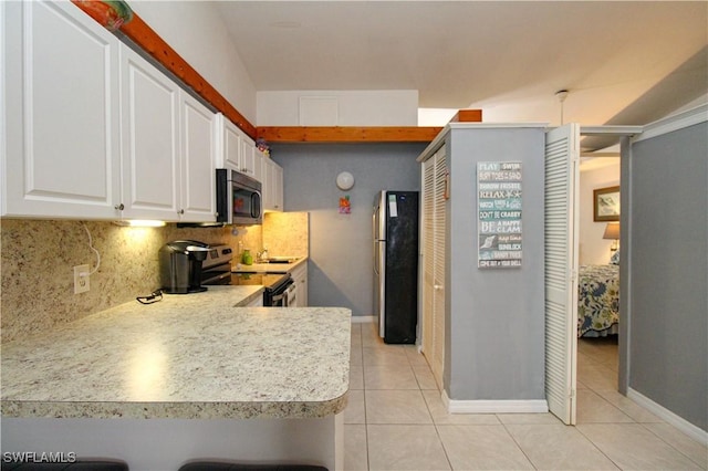826 Wiggins Pass Rd Unit 306, Naples, FL 34110 - kitchen featuring appliances with stainless steel finishes, light tile patterned floors, backsplash, white cabinets, and light countertops