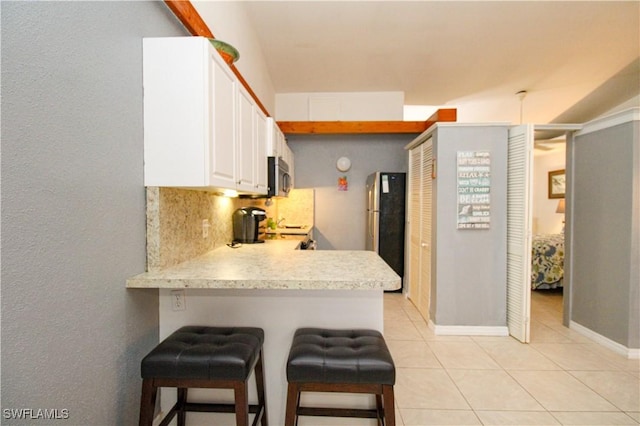 826 Wiggins Pass Rd Unit 306, Naples, FL 34110 - kitchen featuring appliances with stainless steel finishes, light countertops, light tile patterned floors, white cabinetry, and a peninsula
