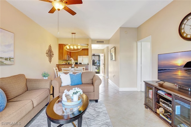 living area with a chandelier, ceiling fan, light tile patterned flooring, and baseboards