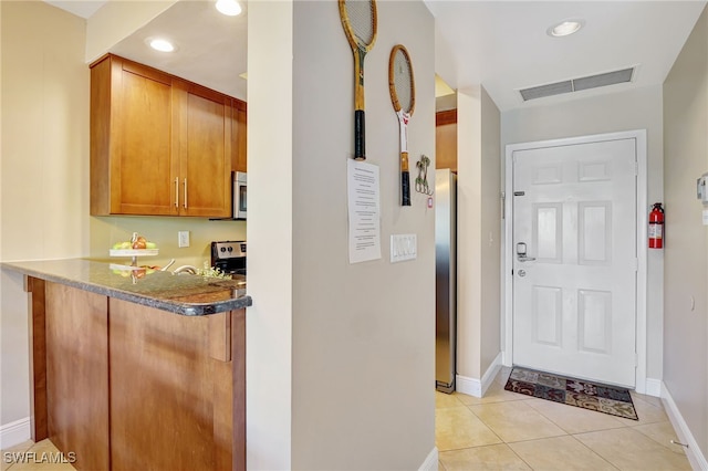kitchen with appliances with stainless steel finishes, baseboards, brown cabinetry, light tile patterned flooring, and recessed lighting
