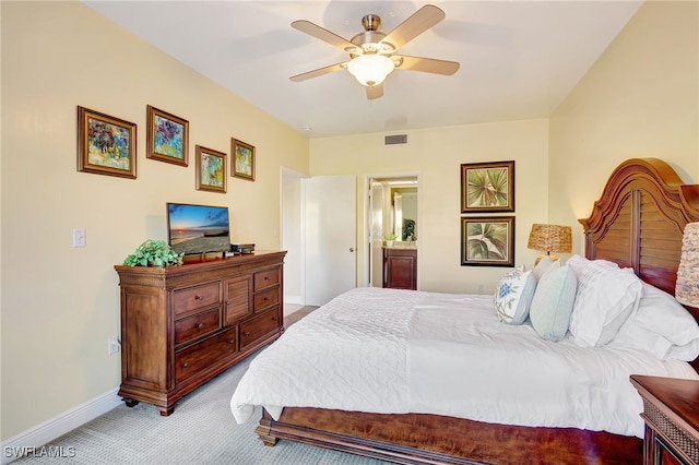 bedroom featuring light colored carpet, baseboards, a ceiling fan, and ensuite bath