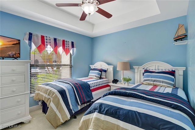 bedroom featuring carpet, a tray ceiling, a ceiling fan, and baseboards