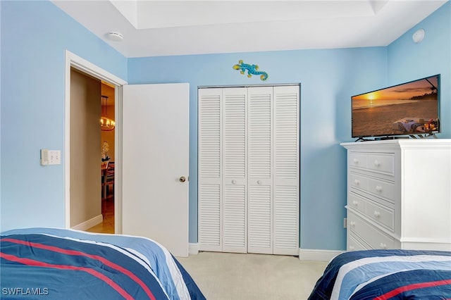 bedroom with light carpet, baseboards, and a closet
