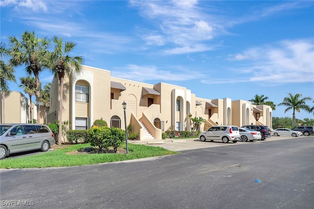 view of building exterior featuring uncovered parking and a residential view