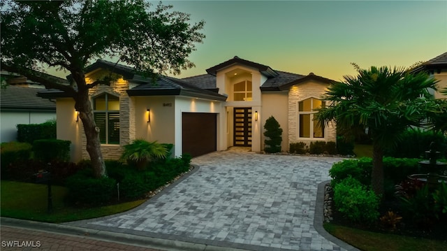 18492 Miromar Lakes Blvd W, Miromar Lakes, FL 33913 - view of front facade with an attached garage, decorative driveway, stucco siding, and stone siding