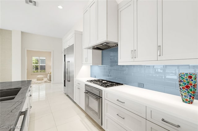 18492 Miromar Lakes Blvd W, Miromar Lakes, FL 33913 - kitchen featuring stainless steel appliances, backsplash, white cabinetry, a sink, and light tile patterned floors