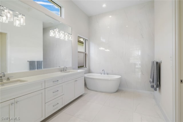 18492 Miromar Lakes Blvd W, Miromar Lakes, FL 33913 - full bathroom featuring marble look tile flooring, a freestanding tub, double vanity, and tile walls