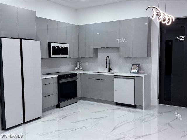 kitchen with white appliances, a sink, gray cabinetry, light countertops, and hanging light fixtures
